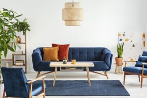 Blue mid century modern living room furniture set with red and orange pillows, small coffee table, and plants in Springfield, IL