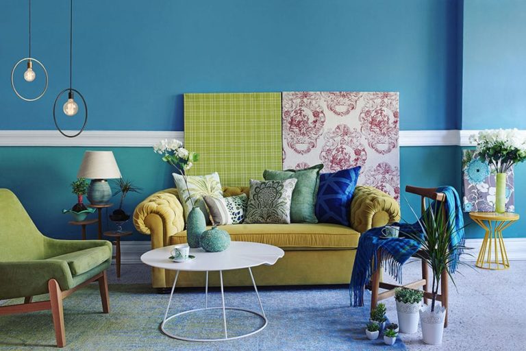 Residential living room with a blue wall, yellow couch, green chair, and colorful décor in Athens, IL.