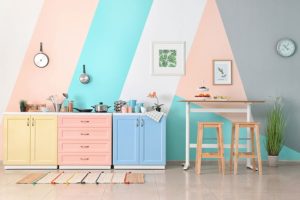 Small colorful kitchen with yellow, pink, and blue cabinets with colorful striped walls and simple décor in Athens, IL.