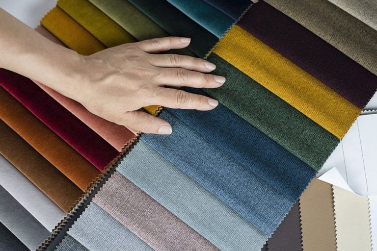 A person laying their hand on a variety of fabric colors for reupholstering a piece of furniture for their home in Springfield, IL